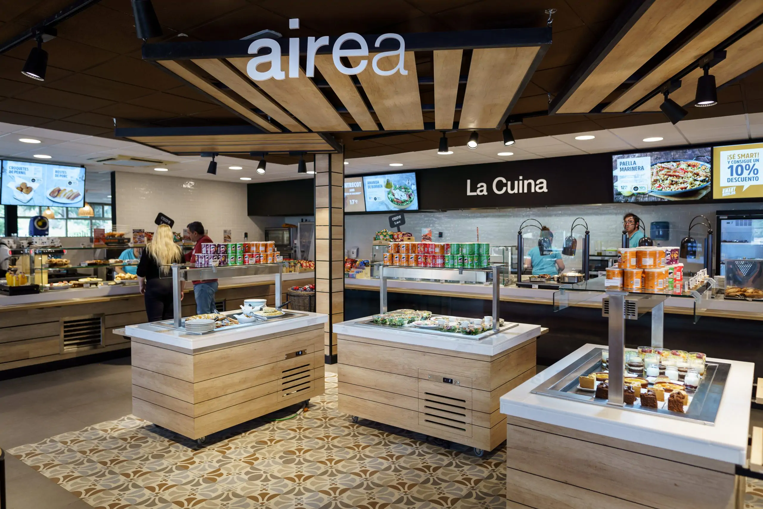 Área de autoservicio “Airea” con mostradores de comida y personal atendiendo.