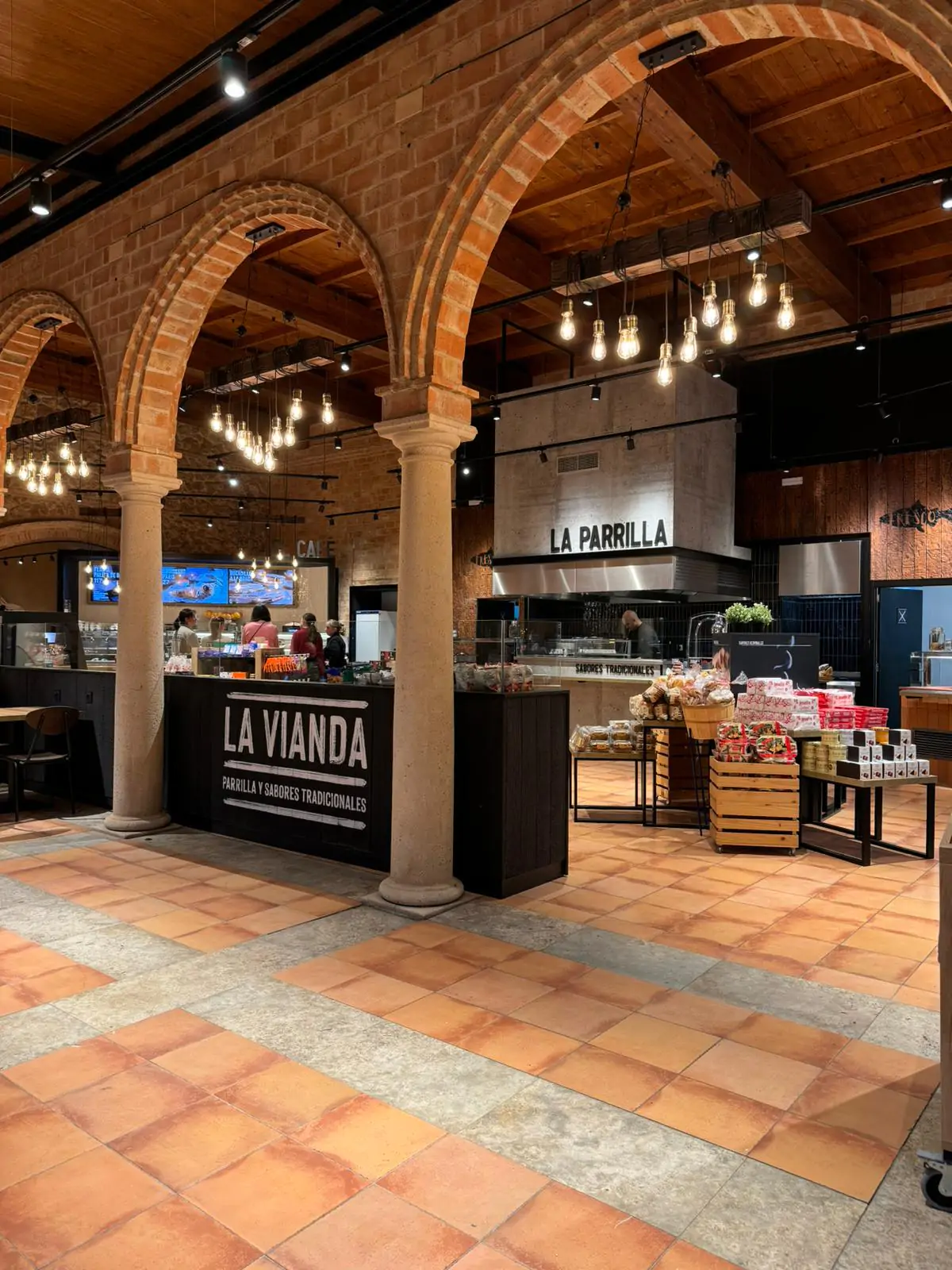 Restaurante con parrilla y mostrador de comida tradicional bajo arcos de ladrillo.