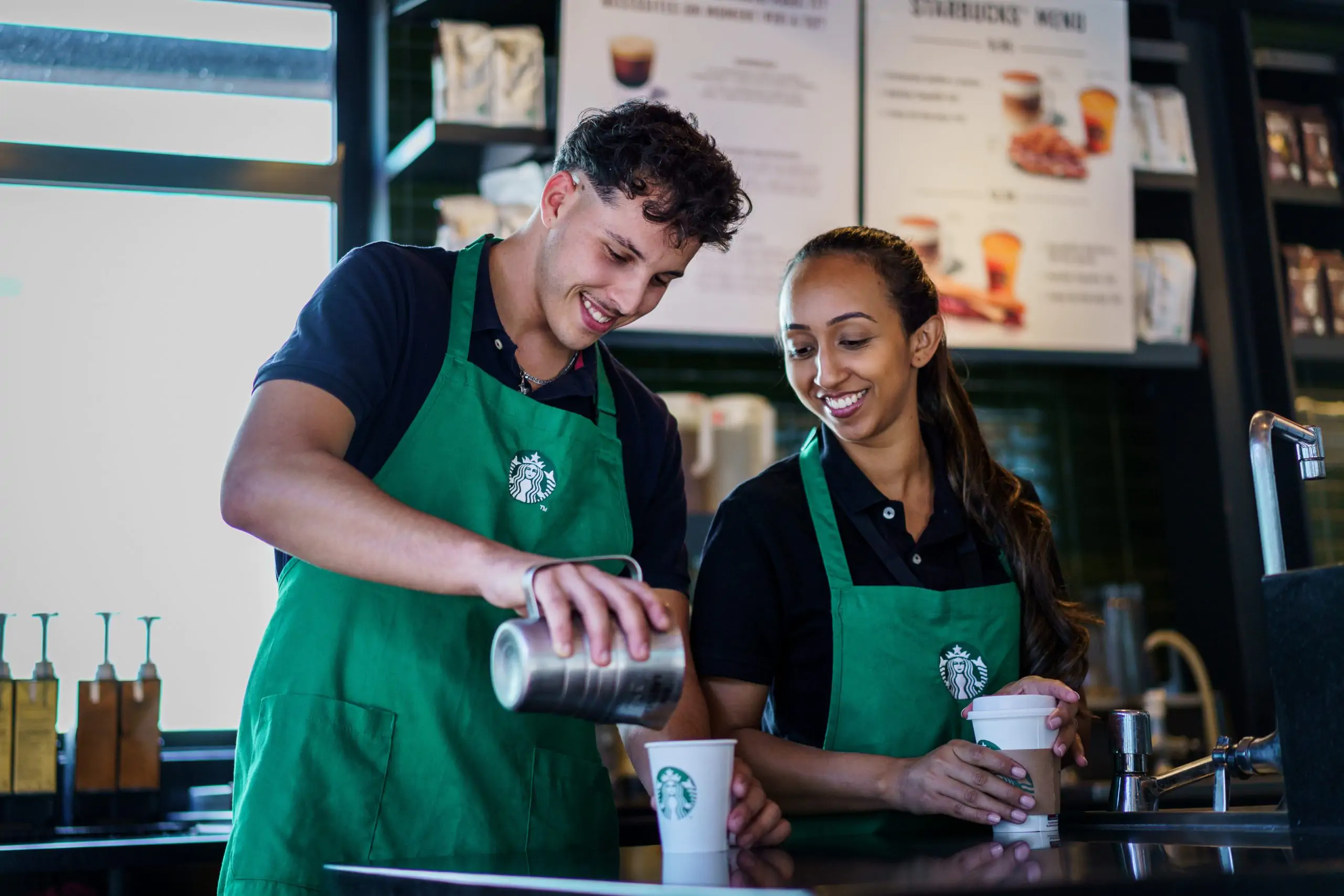 Dos baristas preparando café en mostrador.