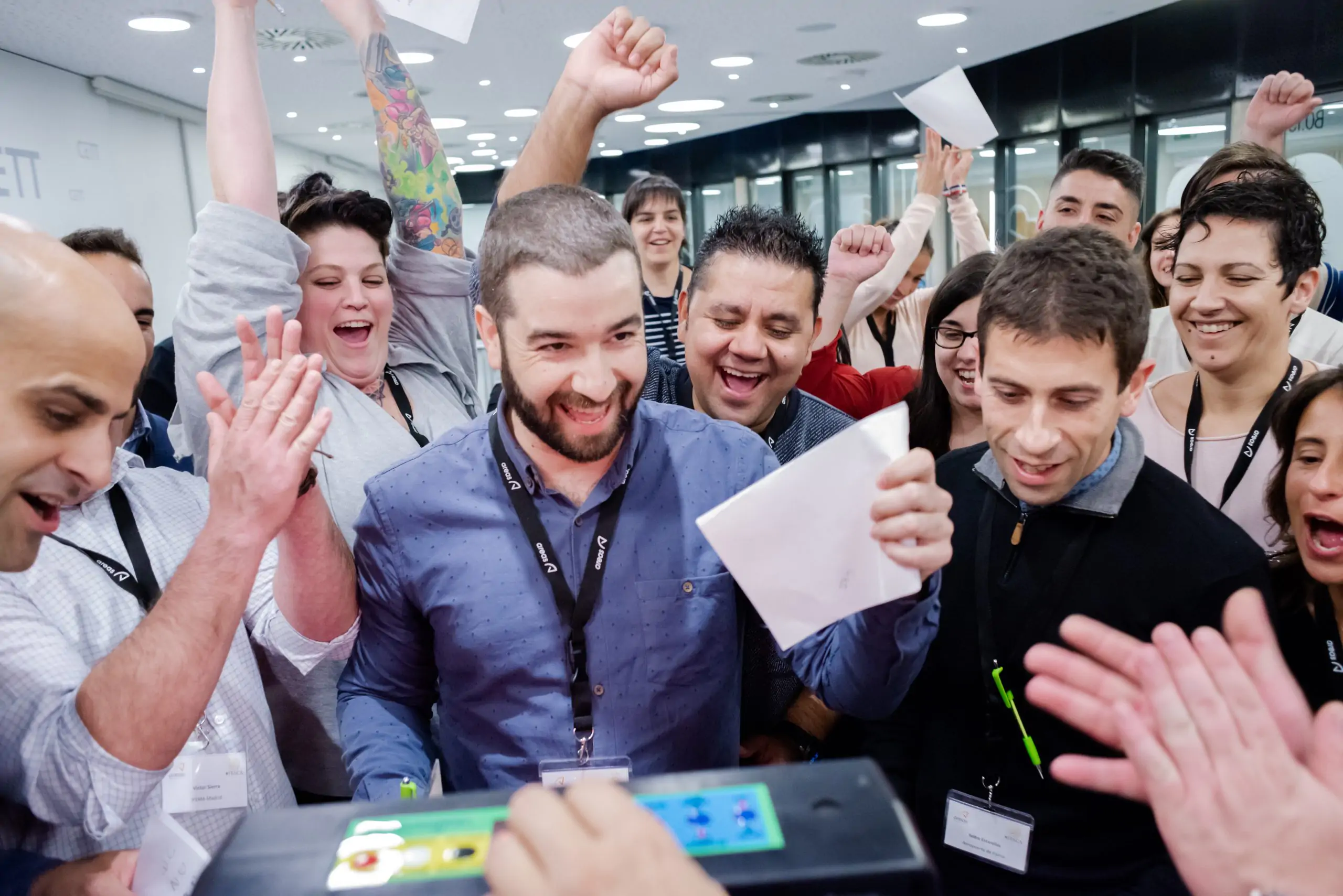 Equipo celebrando juntos en una oficina con documentos en la mano.