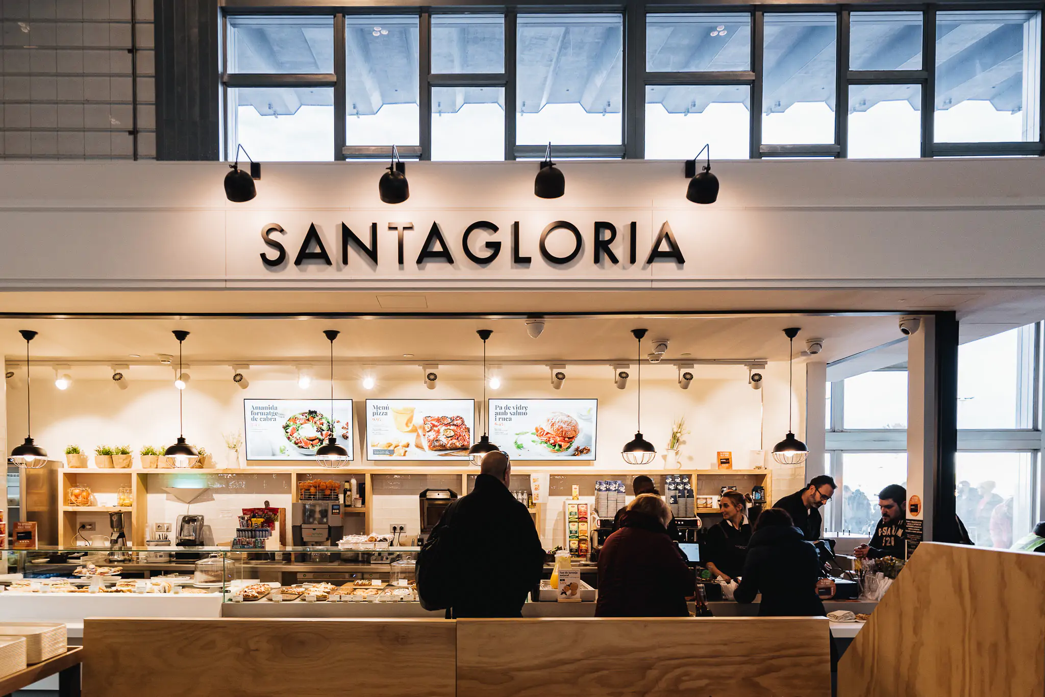 Interior de Santagloria con mostrador de panadería y clientes atendidos.