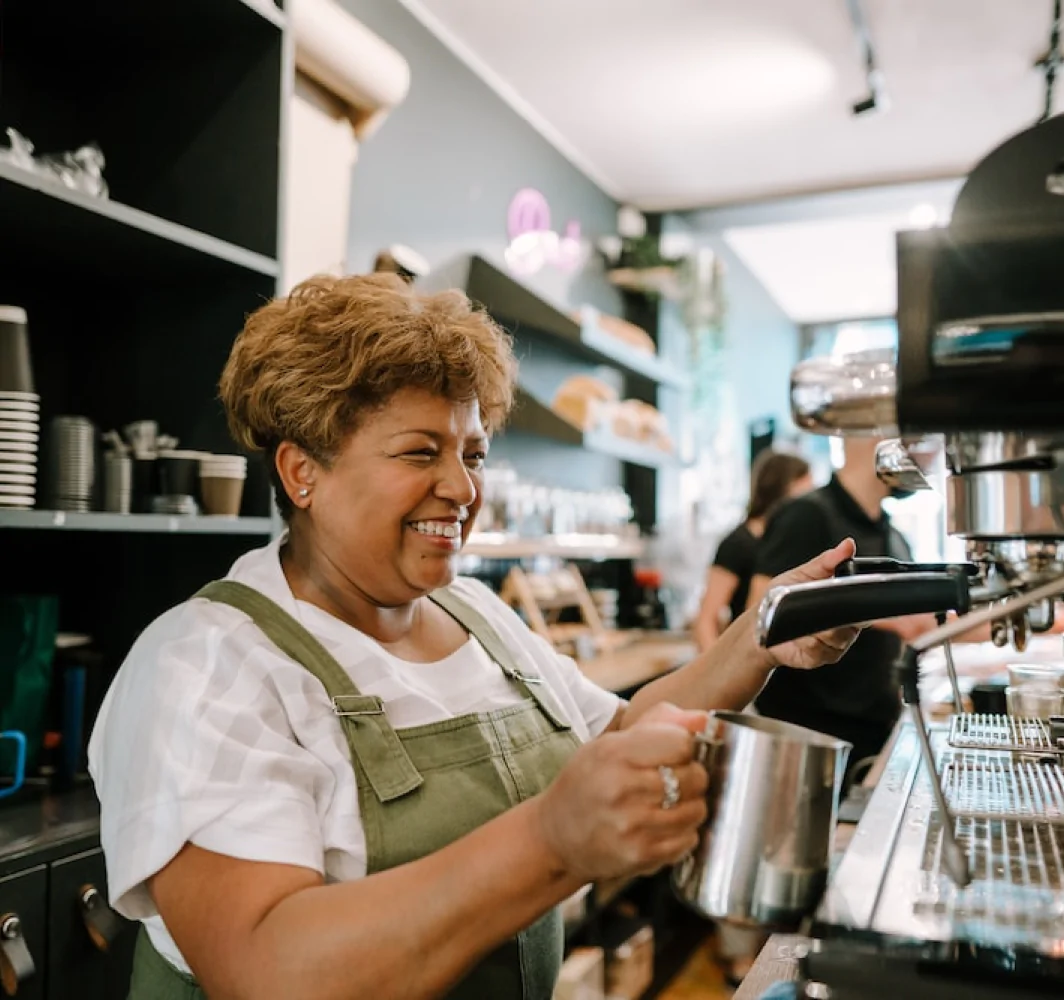 Barista sonriendo mientras prepara café en máquina profesional.
